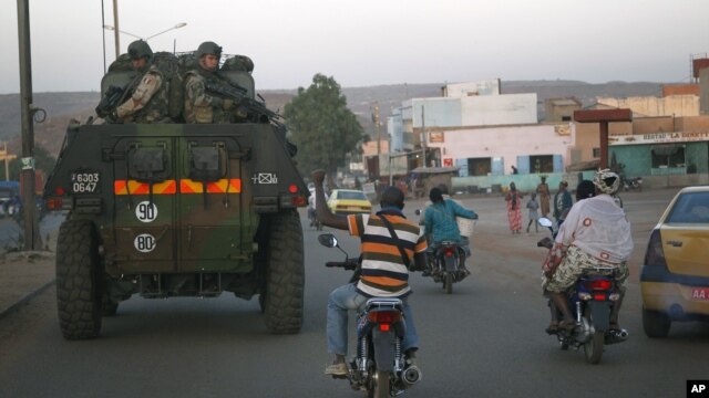 A motorcyclist waves his support as French troops in two armored personnel carriers drive through Mali's capital Bamako on the road to Mopti, January 15, 2013. 