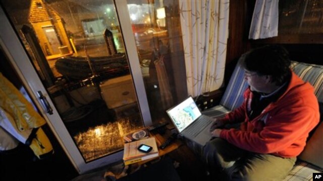 David C. Bond of Wickford, R.I. checks weather forecasts on his computer while riding out Sandy on his boat docked in Annapolis, Md. Monday, Oct. 29, 2012. Sandy continued on its path Monday, as the storm forced the shutdown of mass transit, schools and f