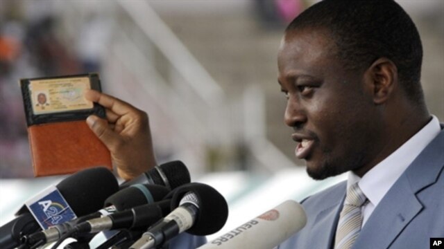 Prime Minister of Ivory Coast  Guillaume Soro displays his identity card as he speaks during a rally at a stadium in Bouake on 3 Oct 2010