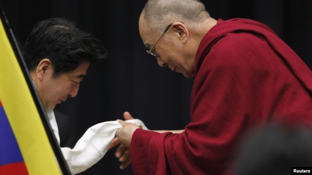 The Dalai Lama gives a Tibetan shawl to Japan's main opposition Liberal Democratic Party president Shinzo Abe, at the upper house members' office building in Tokyo, November 13, 2012.