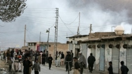 Local residents gather at a road as smoke rise from the site of a bomb blast in a market in Quetta, Pakistan, Feb. 16, 2013.