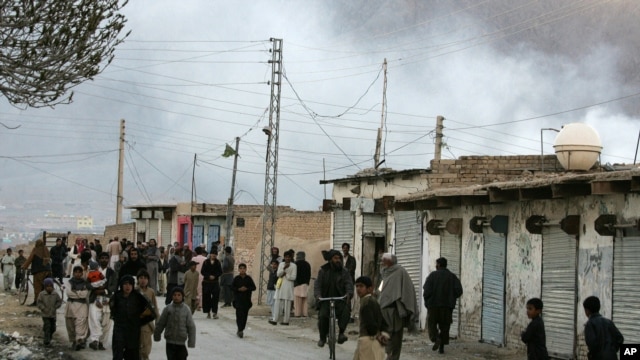 Local residents gather at a road as smoke rise from the site of a bomb blast in a market in Quetta, Pakistan, Feb. 16, 2013.