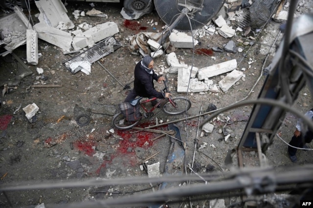 A Syrian man walks with a bicycle amid the rubble of destroyed buildings following a reported air strike by Syrian government forces in the rebel-held area of Douma, east of the capital Damascus, on Oct. 29, 2015.