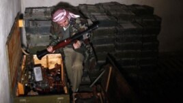 A Free Syrian Army fighter checks weapons which were seized at the army base in Hawa village, north Aleppo, December 23, 2012. 