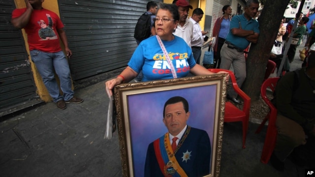 Una mujer sostiene una pintura del presidente Hugo Chávez: el tema de su juramentación también ha regresado a Venezuela.