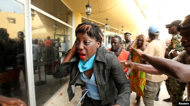 An injured supporter of Ivory Coast's Laurent Gbagbo reacts outside the premises of Hotel Golf, where Gbagbo was being held after his arrest, in Abidjan, April 11, 2011. 