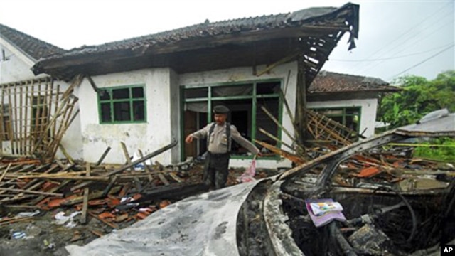 A police officer inspects the damage at the house of a member of Ahmadiyah sect after it was attacked by Muslim mob in Pandeglang, Banten province, Indonesia, February 7, 2011