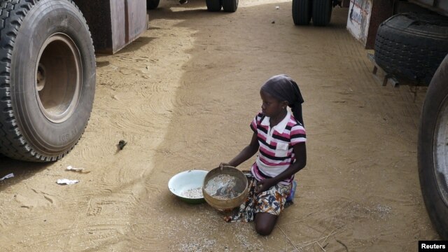 A girl gathers rice spilled from a humanitarian food convoy in the northeastern city of Gao, Mali, June 14, 2012.