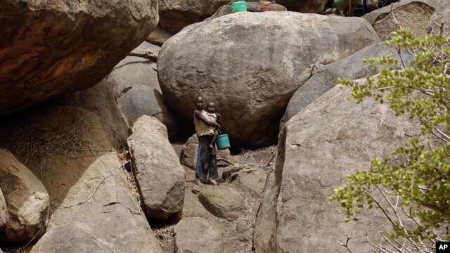 Children stand outside a cave shelter in Tess village in the rebel-held territory of the Nuba Mountains in South Kordofan May 2, 2012. 