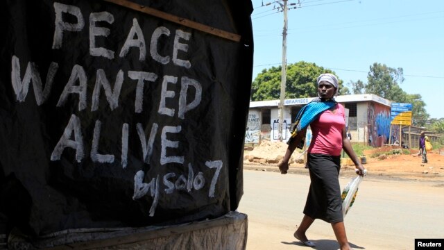 A woman walks past a message of peace in Kibera slum in the capital Nairobi, February 28, 2013.