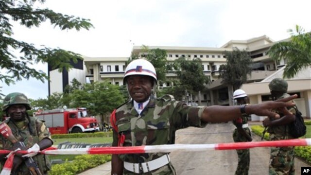 A Nigerian military policeman directs U.N. workers to another entrance, as he stands guard where a day earlier a suicide bomber crashed through an exit gate and detonated a car full of explosives in the reception area of U.N. headquarters, in Abuja, Augus