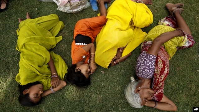 Indian villagers sleep in the shade of a tree on a hot summer day in Allahabad, India