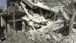 An activist takes photos of a building damaged after a Syrian Air Force fighter jet fired missiles on Erbeen, near Damascus, October 27, 2012. 