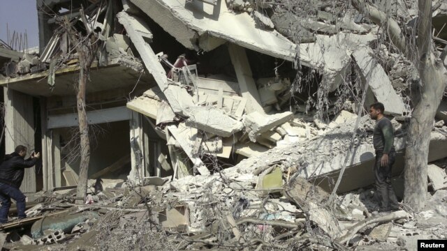 An activist takes photos of a building damaged after a Syrian Air Force fighter jet fired missiles on Erbeen, near Damascus, October 27, 2012. 