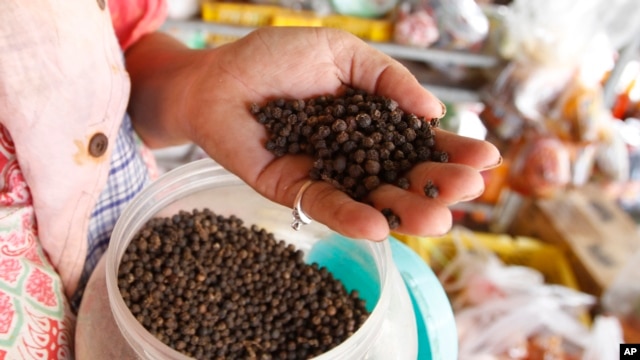 A vendor holds a handful of Kampot pepper before selling at a market in Phnom Penh, Cambodia, Tuesday, March 1, 2016.