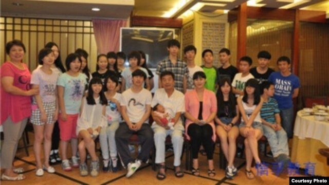 信力建（中）与部分收养的孩子（信孚教育集团网站图片）