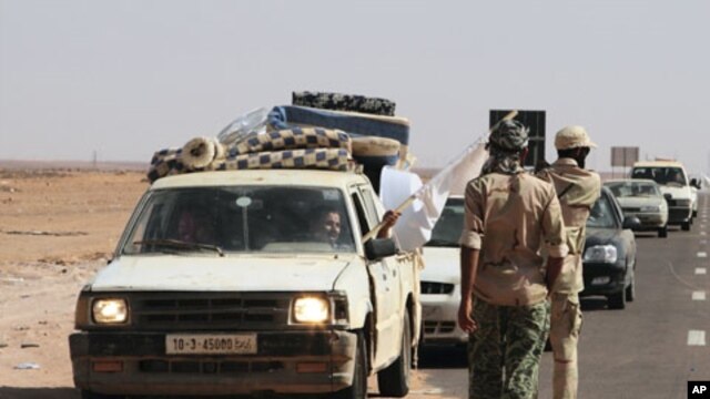 A man waves a white flag from a car loaded with his family and their belongings at a rebel checkpoint 99 miles (160 kilometers) from Sirte, Libya, August 28, 2011