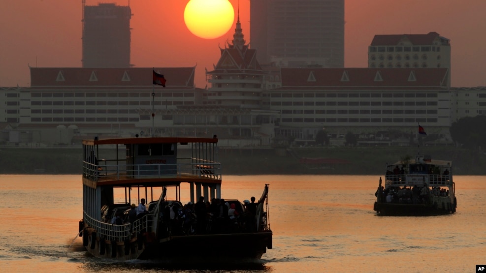 FILE - Ferries transport villagers, students and civil servants from Phnom Penh to Arey Ksat across the Mekong River as the sun sets in Phnom Penh, Cambodia, Saturday, Jan. 31, 2015. (AP Photo/Heng Sinith)