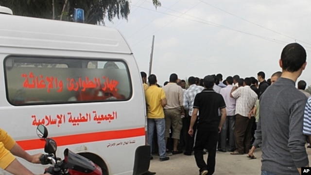 Lebanese civil defense ambulance, civilians gather at site where a cameraman was shot near Wadi Khaled, April 9, 2012.