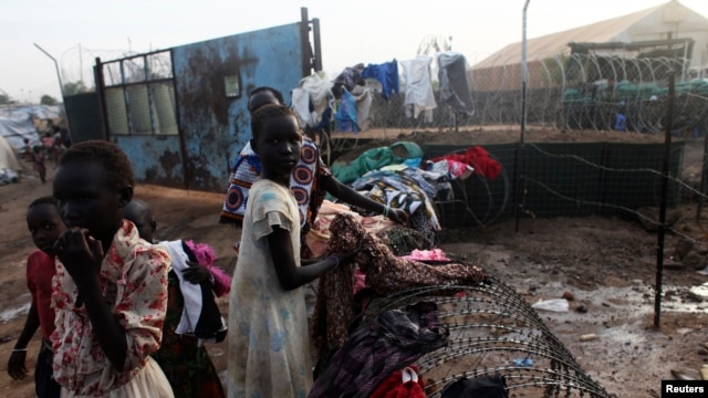 South Sudanese girls displaced by fighting collect their laundry from a barbed wire in a camp for displaced persons in the UNMISS compound in Tomping in Juba February 19, 2014.
