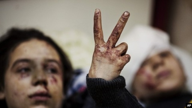 Hana, 12, flashes the victory sign next to her sister Eva, 13, as they recover from severe injuries after the Syrian Army shelled their house in Idlib, north Syria. (March 10, 2012 file photo)