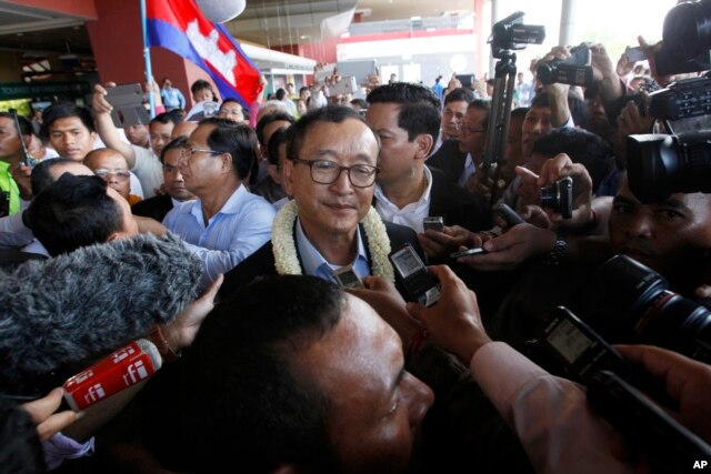 FILE - Sam Rainsy, center, leader of the opposition Cambodia National Rescue Party (CNRP), talks to journalists upon his arrival at Phnom Penh International Airport in Phnom Penh, Cambodia, Aug. 16, 2015.