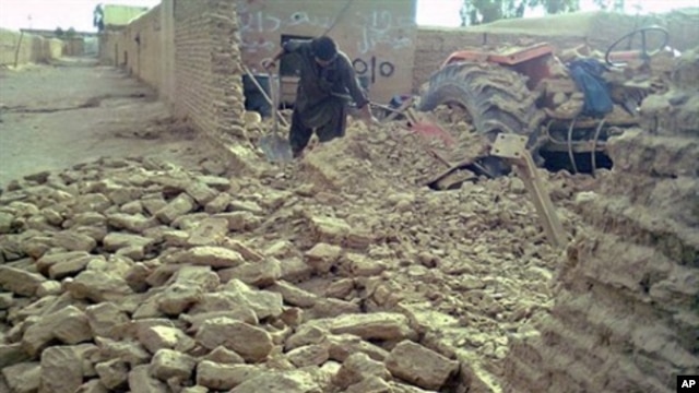 A local resident clears debris of his collapsed mud house following an earthquake in the town of Dalbandin on  19 Jan. 2011.