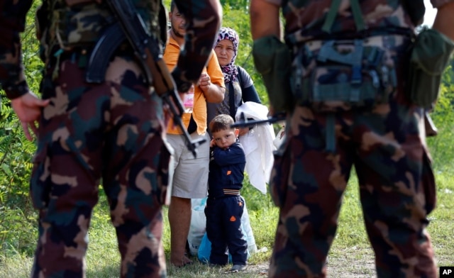 Binh sĩ Hungary chặn một gia đình người nhập cư tại lối ra biên giới giữa Serbia và Hungary, ngày 15/9/2015.