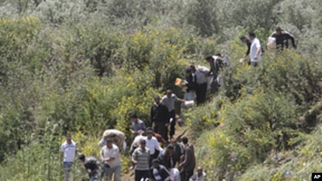 Syrian citizens carry their belongings, as they cross the border illegally , fleeing from violence the western Syrian village of Talkalakh, in the Wadi Khaled area, about one kilometer (0.6 miles) from the Lebanon-Syria border, north Lebanon,  May 16, 201