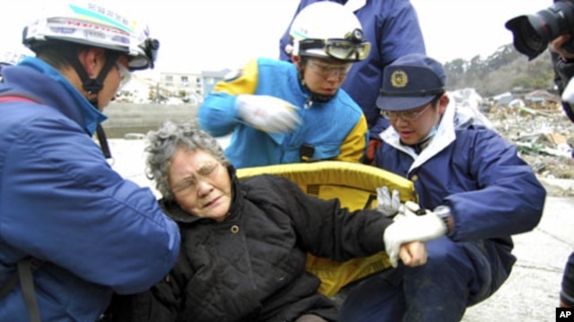 80-year-old Sumi Abe (C) is helped by emergency workers after being rescued from under the rubble in Ishinomaki City, Miyagi Prefecture, northern Japan, in this picture taken by Nikkei Shimbun on March 20 , 2011