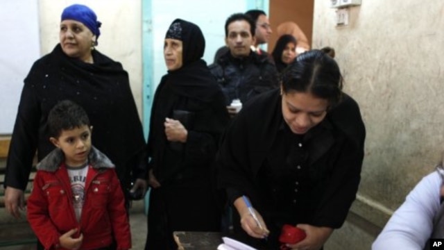An Egyptian woman registers to vote while others are lining up at a polling center in Giza, Egypt, December 21, 2011.