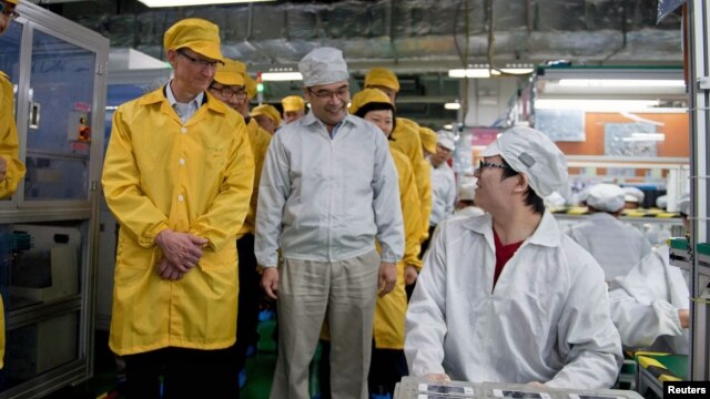 Tim Cook, izquierda, visita una línea de producción de iPhone en China. Un modelo de Mac será fabricado en Estados Unidos.