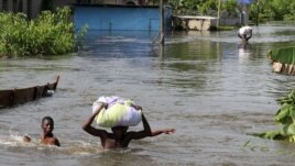 People wade through a flood with their belongings after their houses were submerged in the Amassoma community in Bayelsa state, Nigeria, October 6, 2012. 