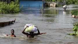 People wade through a flood with their belongings after their houses were submerged in the Amassoma community in Bayelsa state, Nigeria, October 6, 2012. 