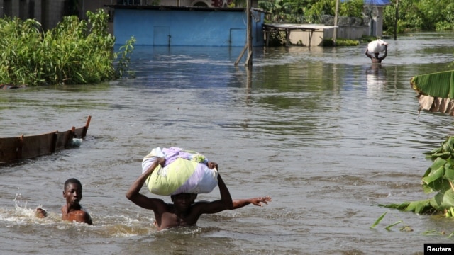 People wade through a flood with their belongings after their houses were submerged in the Amassoma community in Bayelsa state, Nigeria, October 6, 2012. 