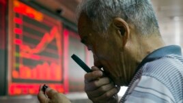 Một nhà đầu tư Trung Quốc sử dụng kính lúp để nhìn vào điện thoại di động khi ông theo dõi giá cổ phiếu ở Bắc Kinh hôm 9/7/2015.