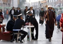 2009年6月19日保安人员在西藏首府拉萨观察走在八廓街上的佛教朝圣者