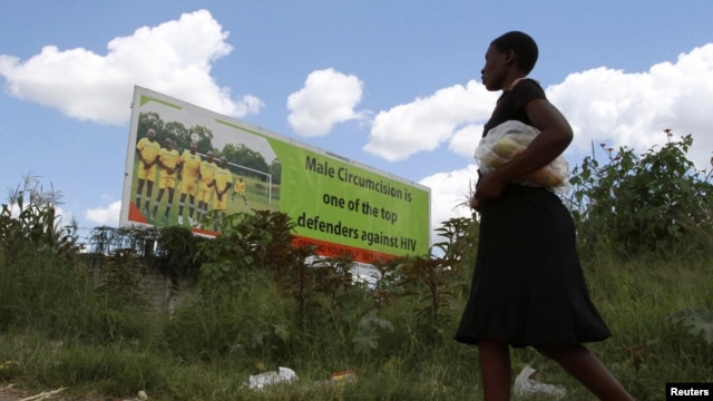 A Zimbabean woman walks past a billboard promoting male cirumcision to combat AIDS in the capital (Philimon Bulawayo/Reuters)