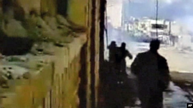 Protesters watch as tear gas fills a street during a demonstration in Deraa in this image from amateur video taken on Mar 23 2011 and posted on a social media website