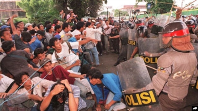 Indonesian students fall as riot policemen charge-in during an anti-government demonstration that turned violent at the gate of the Sahid University in Jakarta 29 April, 1998.  Clashes erupted as some 300 students who were demanding President Suharto to s