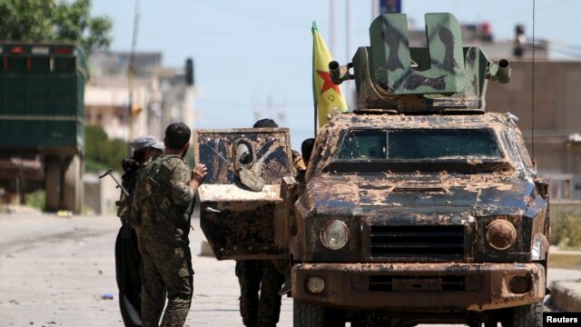 Kurdish fighters from the People's Protection Units (YPG) stand near a military vehilce in the southeast of Qamishli city, Syria, April 22, 2016.