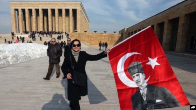 People hold national flags with posters of the founder of modern Turkey Kemal Ataturk as they visit his mausoleum in Ankara, Turkey, February 5, 2012.