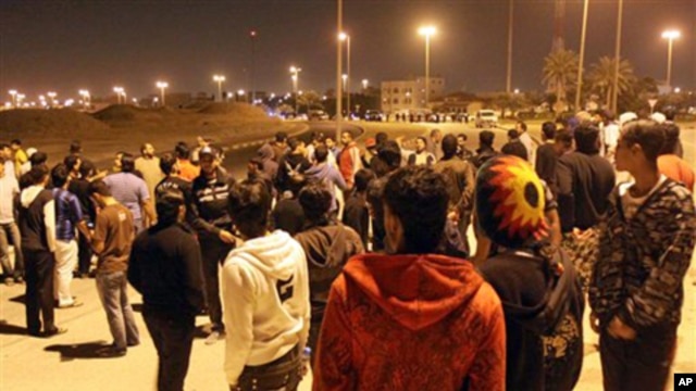 A row of riot police stand between two groups of Bahraini youths in the early hours of Friday in Hamad Town, March 4, 2011