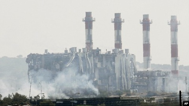 Smoke is seen in front of a damaged building by the power station in Mari on July 11, 2011 after huge explosions, reportedly from seized munitions, rocked the nearby Greek-Cypriot "Evangelos Florakis" naval base leaving several dead and injured.