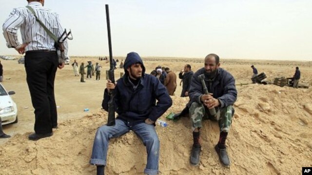 A rebel holds a gun on the outskirts of Ajdabiya, on the road leading to Brega, Libya, March 2, 2011
