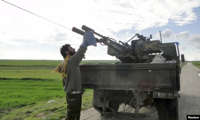 FILE - A Free Syrian Army fighter cleans an anti-aircraft artillery gun near the Menagh military airport in Aleppo's countryside, Feb. 17, 2013.