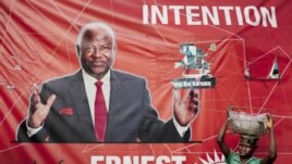 A child street vendor stands in front of a poster for Sierra Leone's ruling party presidential candidate Ernest Bai Koroma, Freetown, Nov. 16, 2012.