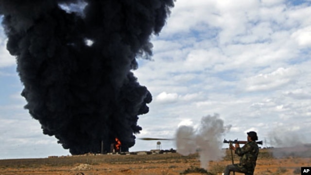 A rebel fighter fires a rocket-propelled grenade in front of a gas storage terminal during a battle on the road between Ras Lanuf and Bin Jiwad, Mar 9 2011