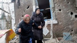 Cư dân đi bộ bên ngoài một ngôi nhà bị hư hại bởi pháo kích ở Donetsk, miền đông Ukraine, ngày 3/2/2015.