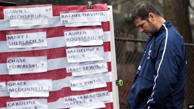 Un hombre apesadumbrado frente a una bandera cubierta con los nombres de las víctimas de Newtown.